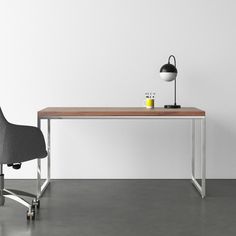 a desk with a chair and a lamp on it in front of a white wall