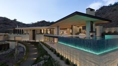 a modern house with an outdoor swimming pool and waterfall in the front yard at night