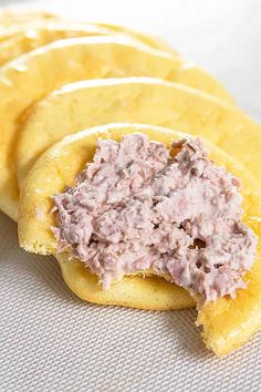 crackers with tuna spread on them sitting on a white tableclothed surface, ready to be eaten