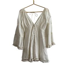 Alice + Olivia Alexandria Open Back Tunic Dress In Off-White. New With Tags - Several Small Flaws From Storage (Last 2 Pictures). I Have Not Tried To Remove. - 100% Cotton - Made In India - Fully Lined - Front Loop Button Closure - Smocked Back With Tie Closure - Kimono Sleeves With Tassel Fringe At Cuffs -Tassel Fringe At Hem - Tiered Voile Fabric With Lace Trim Throughout - Revolve Style No. Ali-Wd900 Approximate Measurements Laying Flat - Pit To Pit 16" Length Shoulder To Hem 31" Cream Long Sleeve Mini Dress For Beach, Flowy Off-white V-neck Mini Dress, Flowy Off White V-neck Mini Dress, Off White Flowy V-neck Mini Dress, Long Sleeve Off-white Mini Dress For Beach, White Long Sleeve Summer Boho Dress, Off-white Long Sleeve Mini Dress For Beach, Off White Long Sleeve Mini Dress For Beach, Off White V-neck Mini Dress For Beach