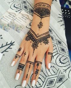 a woman's hand with henna tattoos on it