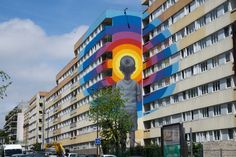 a large mural on the side of a multi - colored building in front of a parking lot