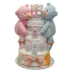 a diaper cake with two teddy bears on top and baby items around the base