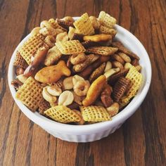 a bowl filled with chex mix on top of a wooden table