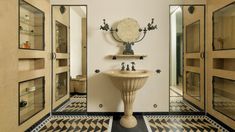 a bathroom with black and white checkered flooring, an ornate pedestal sink and mirror