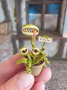 someone is holding a tiny toy plant with two eyes and a mouth on it's head