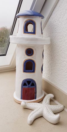 a white and blue lighthouse next to a starfish on the ground near a window