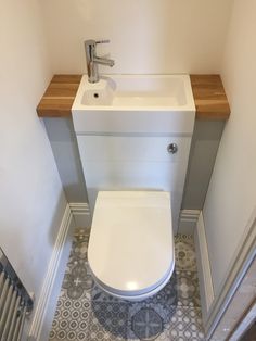 a white toilet sitting next to a sink under a faucet in a bathroom