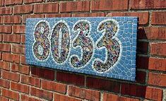 a brick wall with a blue and white mosaic tile sign on it's side