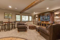 a living room filled with furniture and a flat screen tv mounted to the wall next to a bar