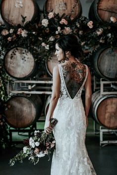 a woman in a wedding dress standing next to some wine barrels with flowers on them