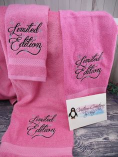 two pink towels with black lettering and a penguin on the front one has a name tag