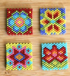 four different colored squares made out of legos on top of a wooden table,