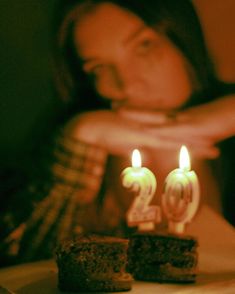 a woman is looking at two candles in the shape of numbers on a piece of cake