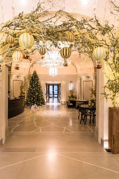 the lobby is decorated for christmas with balloons and decorations on the ceiling, as well as trees