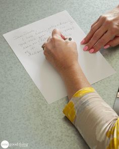 a woman is writing on a piece of paper with a pen and scissors next to her