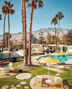 palm trees and lawn chairs in front of a swimming pool with mountains in the background