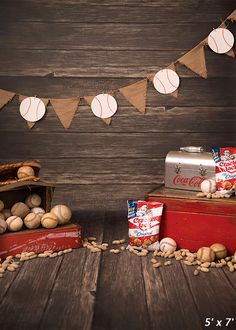 some baseballs and cans are sitting on the floor next to a wooden wall with bunting