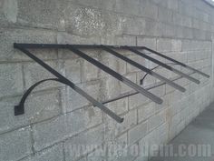 a metal shelf on the side of a brick wall with four bars attached to it