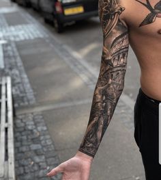 a man with tattoos on his arm standing next to a street