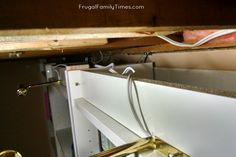 an open cabinet door in a kitchen under the counter top with wires attached to it