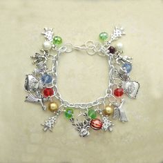 Christmas Charm Bracelet with Red, Blue and Crystal with Gold Pearl. Christmas Tree, Angel, Raindeer, Candy Cane and Santa Claus Charms on 7.5 Inch Silver Charm Bracelet. The bracelet contains Christmas Tree Charms Angel Charms Raindeer Charms Candy Cane Charms Santa Claus Charms Gold Faux Pearl Red Crystal Beads Blue Crystal Beads Green Crystal Beads on Silver 7.5 Inch Charm Bracelets Christmas bracelet red and green Christmas bracelet bead Christmas bracelet charms Christmas charm bracelet Silver Bracelets For Holiday, Silver Bracelet For Holiday, Silver Bracelets For Christmas Festive Season, Festive Silver Bracelets For Christmas, Blue Christmas Jewelry For The Holiday, Silver Holiday Bracelet, Multicolor Festive Bracelets For Christmas, Festive Multicolor Bracelets For Christmas, Christmas Charm Bracelet Gift