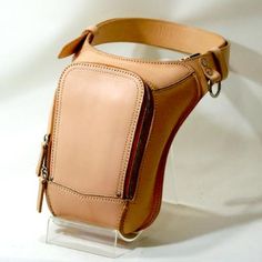 a small tan leather bag on a clear stand with a white background in the photo