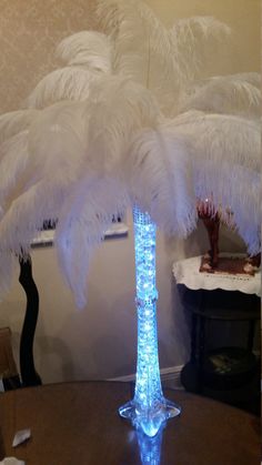 a tall glass vase with white feathers on the top and bottom sitting on a table