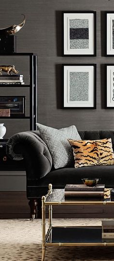 a living room with black couches and pictures on the wall above them, along with a coffee table