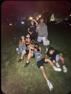 a group of young people sitting on top of a lush green field next to each other