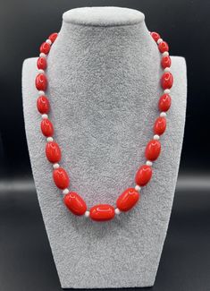 Fiery vintage 1970's single strand necklace featuring tomato-red plastic beads, each separated by a small round white plastic spacer bead.  The combination of white against red gives this necklace a proper pop of colour and 70s charm! This piece measures approximately 18 inches (46cm) long. The red beads are graduated, with the largest central red beads measuring approximately 0.8 inch (2cm), and the smallest red beads measuring approximately 0.5 inch (1.3cm). This was a beloved strand owned and often worn by our own mother. We'd like to think that it has been imbued over the decades with her big laugh and excellent sense of humour! This piece is in good for vintage condition.  It does have some wear on the string along the closure, and some scuffs and marks as one would expect of a pre-lo Red Oval Beaded Single Strand Necklace, Adjustable Red Necklaces With Oval Beads, Adjustable Red Necklace With Oval Beads, Red Necklaces With Large Oval Beads, Red Oval Beaded Necklace, Red Choker With Large Round Beads, Red Polished Pearl Necklace, Red Pearl Necklace With Polished Round Beads, Red Beads