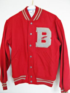 "vintage probably from the 70's, champion knitwear  varsity letterman  jacket *red wool with red/grey striped  knit collar, cuffs, and hem  * *grey \"B\" chenille letter  with red track and field? icon  *metal snap front closure * angled side pockets * unlined.  tags/labels:  champion knitwear, co.  inc. rochester, new york,  made in usa  - medium 38-40 condition:  fair to good vintage, there are a bunch of tiny moth bites, a few larger ones,  and some wear holes around the cuffs mostly. still i Retro Cotton Varsity Jacket For School, Red Varsity Outerwear With Crew Neck, Red Varsity Crew Neck Outerwear, Vintage Hooded Varsity Jacket For Winter, Retro Red Varsity Jacket For Winter, Vintage Cotton Varsity Jacket With Letter Print, Vintage Cotton Varsity Jacket With Ribbed Cuffs, Retro Winter Varsity Jacket With Ribbed Cuffs, Vintage Red Varsity Jacket With Long Sleeves