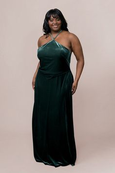 a woman in a long green dress posing for a photo with her hands on her hips