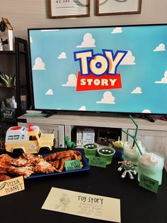 toys and food on a table in front of a television with toy story written on it