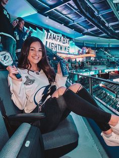 a woman is sitting in the bleachers with her legs crossed and smiling at the camera