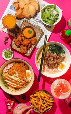 a pink table topped with plates and bowls filled with different types of food next to drinks