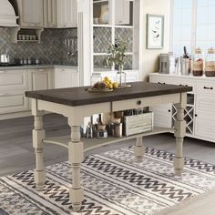 a large kitchen island in the middle of a living room with white cabinets and drawers