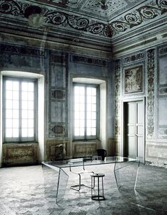 an empty room with two windows and a glass table in the middle, surrounded by marble flooring