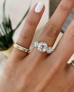 a woman's hand with three different rings on it and one has a white manicure