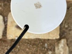 a white frisbee sitting on top of a stone floor next to a black cord