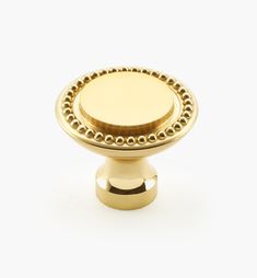 an antique brass knob with beading on the top and bottom, in front of a white background