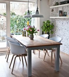 a dining room table with chairs and flowers in vases on the table next to it