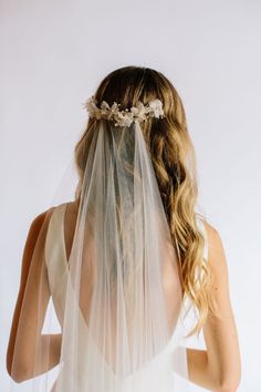 the back of a bride's veil with flowers and leaves on it, against a white background