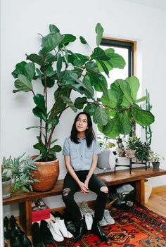 a woman sitting on top of a bench next to a potted plant