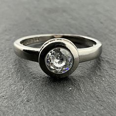 a close up of a ring with a diamond in the center on a gray surface