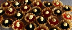 many small pastries are sitting on a plastic tray with red and white toppings