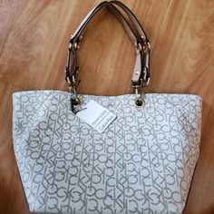 New Calvin Klein Tote Bag With Tag *Authentic* Cream/Beige/Brown/Gold Detachable Handles Reversible Inside Out Tote To Bucket Bag Magnetic Closure 18" L Top 11" L Bottom 11" H Condition Excellent New With Some Minor Scratches On Attachment Of The Handles. Never Been Used. Beige Satchel With Branded Hardware For Daily Use, Trendy Beige Bag With Branded Hardware, Calvin Klein Tote Bag With Removable Pouch, Calvin Klein Shoulder Bag With Adjustable Strap For Shopping, Casual Satchel With Branded Hardware For Daily Use, Casual Satchel With Branded Hardware For Shopping, Casual Beige Bag With Branded Hardware, Casual Shoulder Bag With Branded Hardware For Daily Use, Chic Calvin Klein Tote Bag