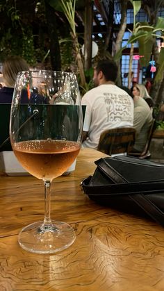 a glass of wine sitting on top of a wooden table