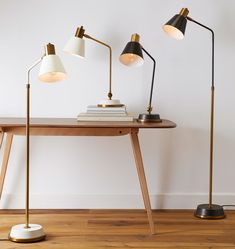 three lamps are sitting on top of a wooden table next to a book and lamp