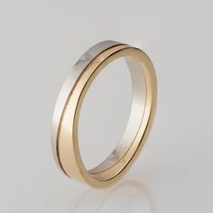 two tone gold wedding ring with white and yellow gold inlays, set on a plain surface